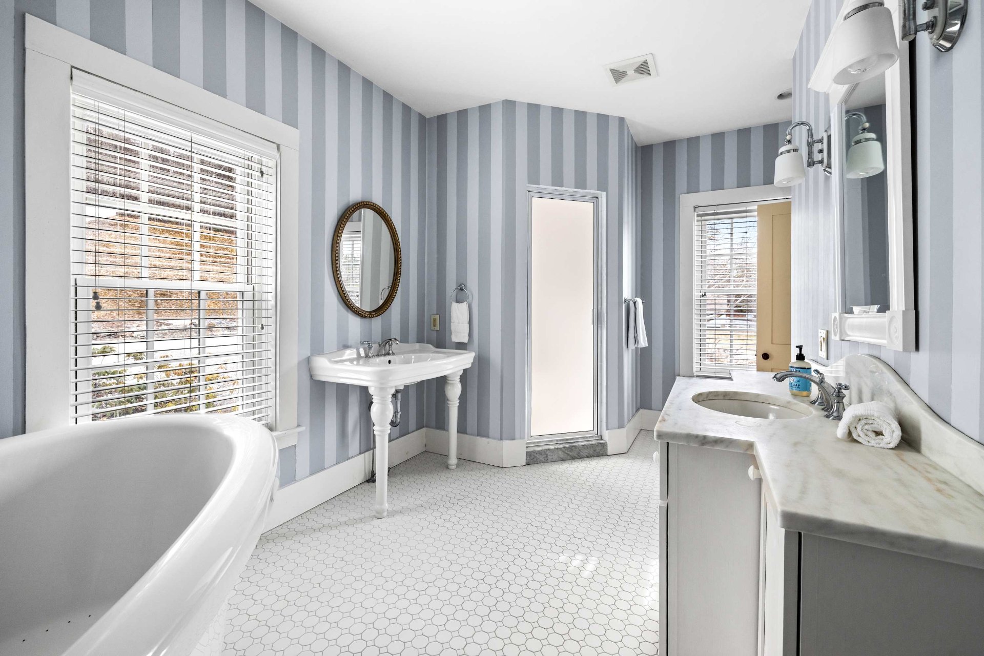 Primary bath with pedestal sink, second marble vanity, and hex tile floor
