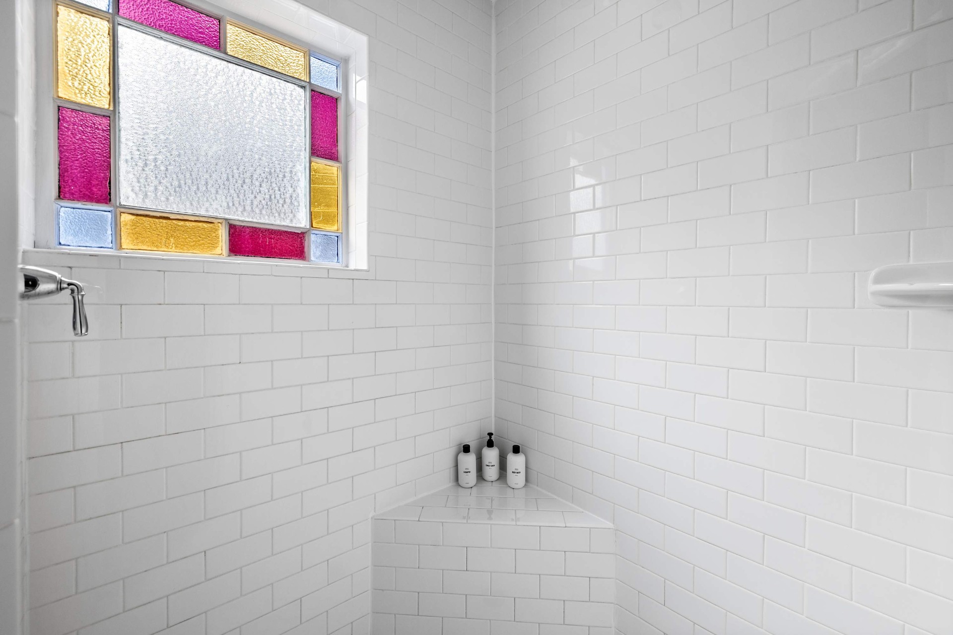 Subway-tiled shower with original stained glass window
